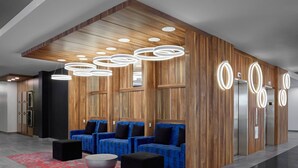 A modern lobby with wooden paneling, blue upholstered seating, and circular light fixtures. - Delta Hotels by Marriott Trois Rivieres Conference Centre (Trois-Rivieres)