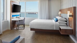 A modern hotel room with a bed, a desk, a chair, a TV, and a view of the sea. - Delta Hotels by Marriott Trois Rivieres Conference Centre (Trois-Rivieres)