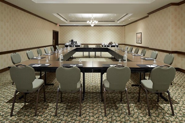 A conference room with a long table, chairs, and a carpeted floor.