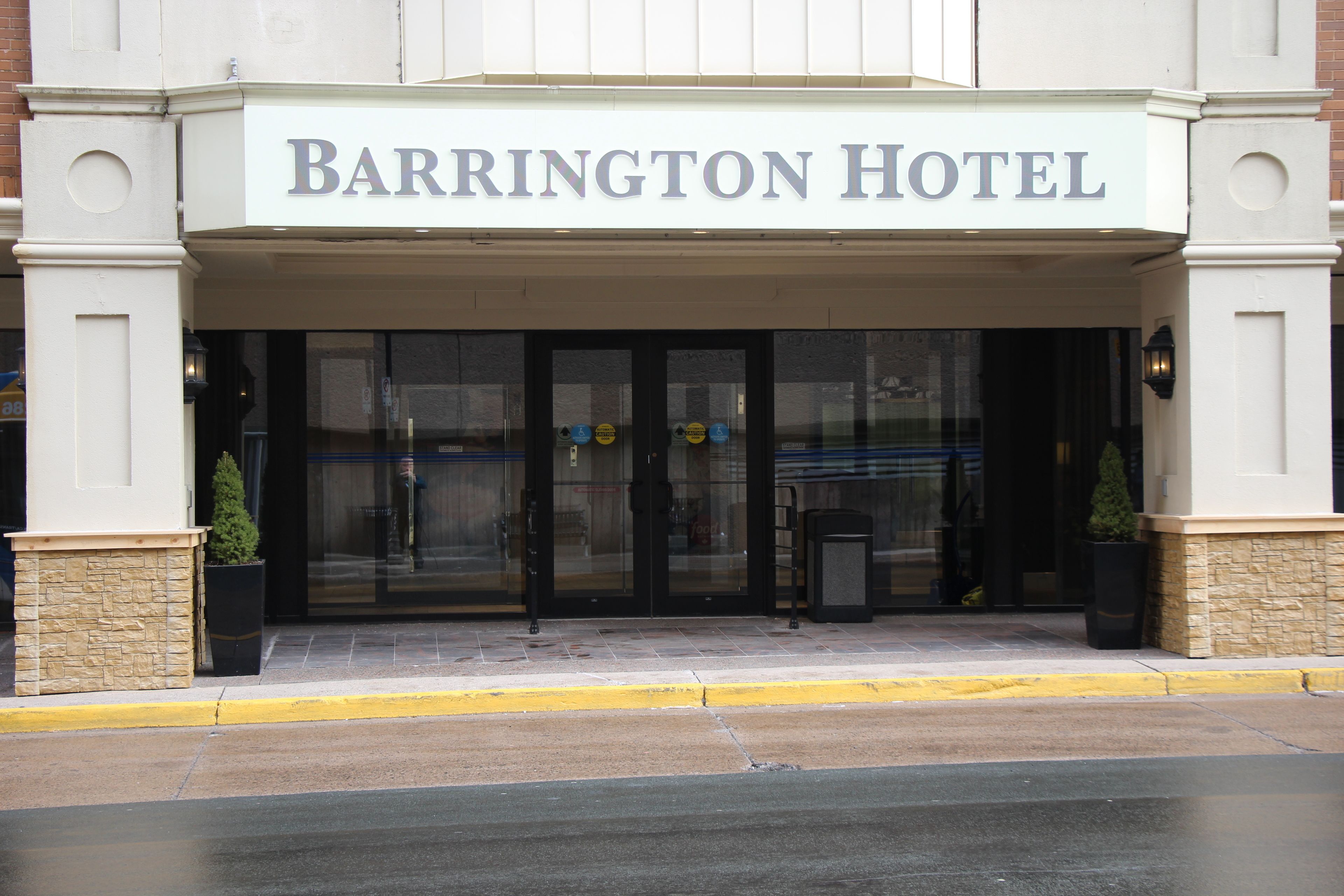 The exterior of Barrington Hotel with a clear entrance, a stone facade, and a sign above the doors.