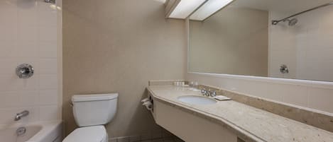 A bathroom with a bathtub, toilet, sink, and a large mirror.