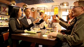 A group of people toasting at a bar with various bottles and glasses.