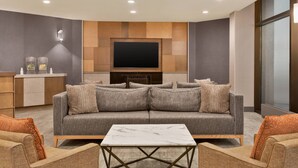 A modern living room with a grey sofa, a marble coffee table, and a flat-screen TV mounted on a wooden wall. - Delta Hotels by Marriott Saint John (Saint John)