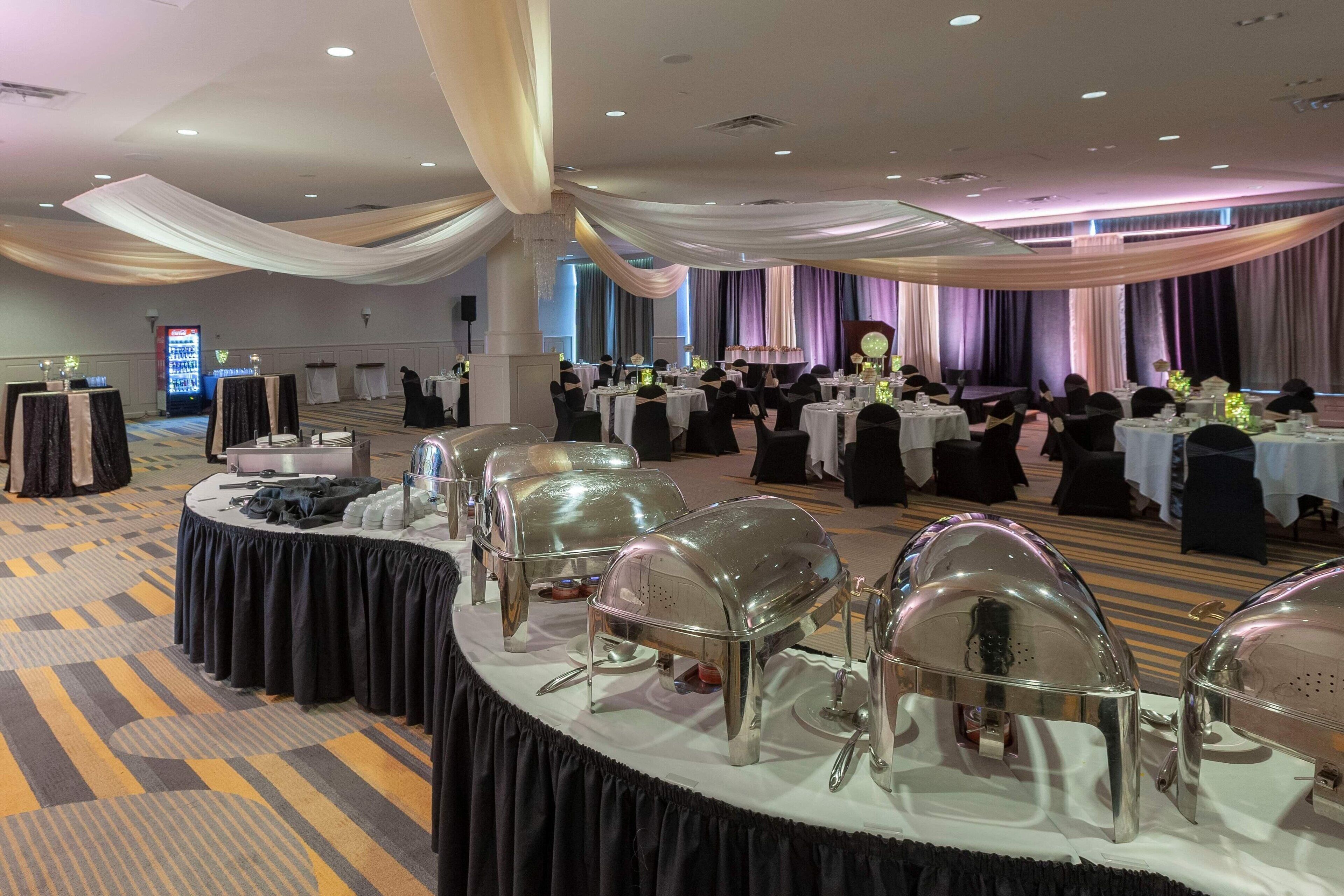 Ein Festsaal mit runden Tischen, Stühlen und Buffet.