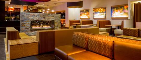 A modern lounge area with leather seating, a stone fireplace, and ambient lighting.