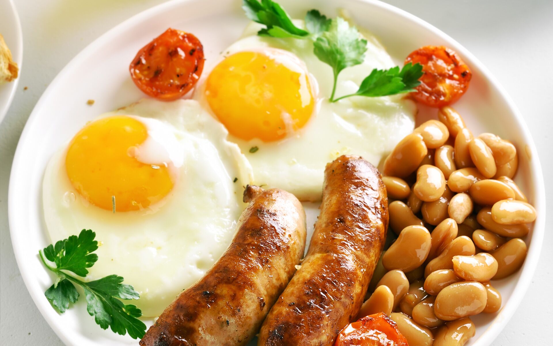 A plate with two fried eggs, sausages, and baked beans.