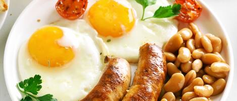 Un plato con dos huevos fritos, salchichas y frijoles horneados.