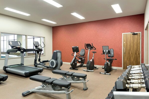 Un gimnasio con cintas de correr, elípticas y bancos de pesas.