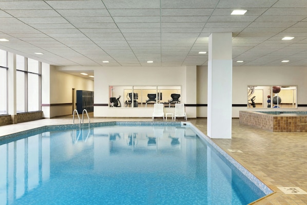 A swimming pool with a tiled deck, a changing room, and a mirrored wall. - Delta Hotels by Marriott Saint John (Saint John)