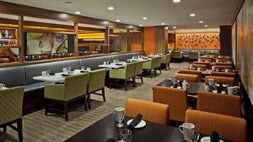 A restaurant with booths and tables, some with napkins and glasses.