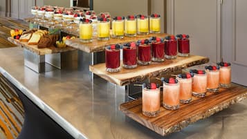Un buffet proposant une variété de fruits et de desserts, notamment des gâteaux, des pâtisseries et des boissons garnies de fruits.
