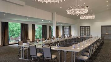 A conference room with a long table, chairs, and chandeliers.