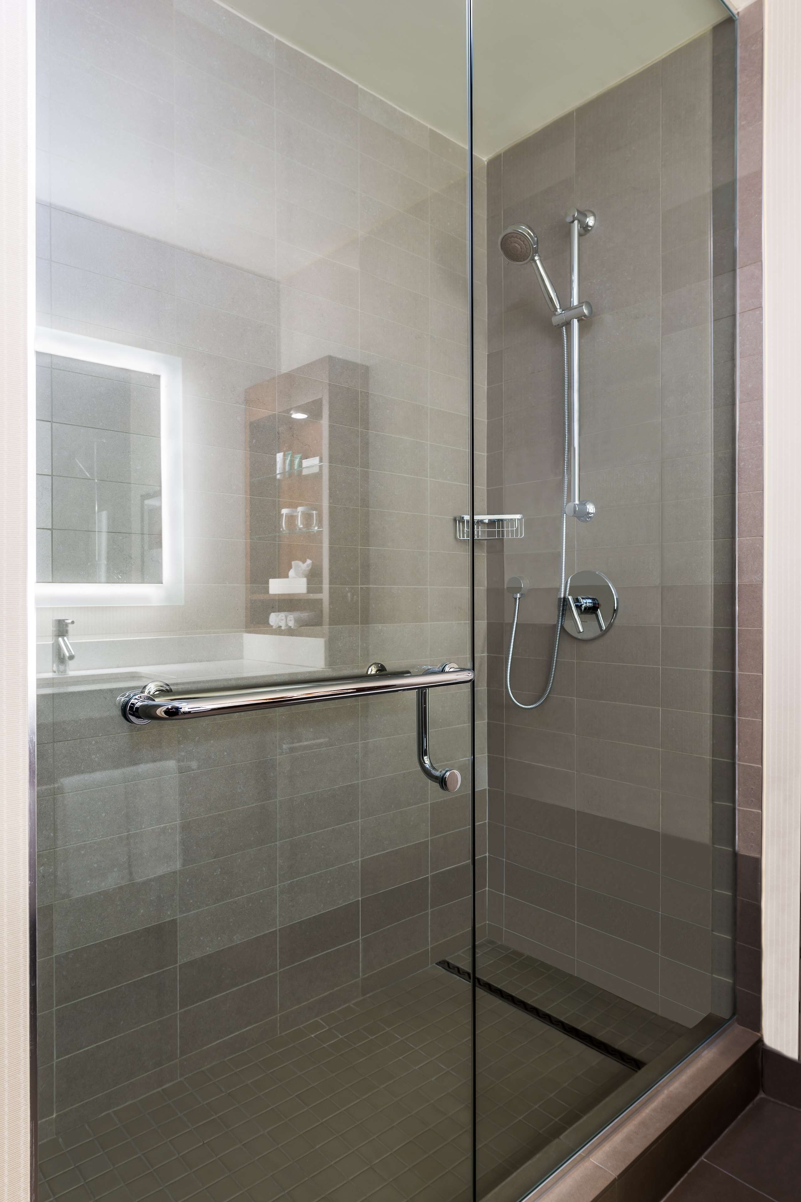 A modern bathroom with a glass shower enclosure, a glass door, and a visible towel rack.