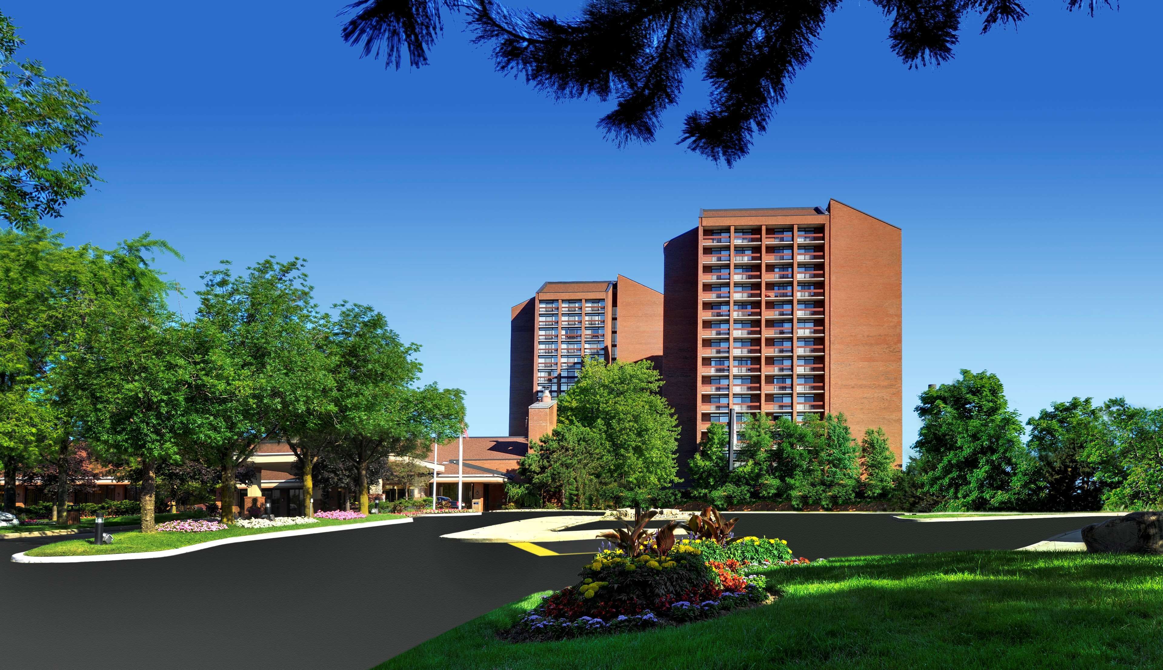 A modern building with a brick facade, surrounded by lush greenery and a well-maintained lawn.