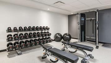 A gym with weightlifting equipment, dumbbells, and exercise balls.