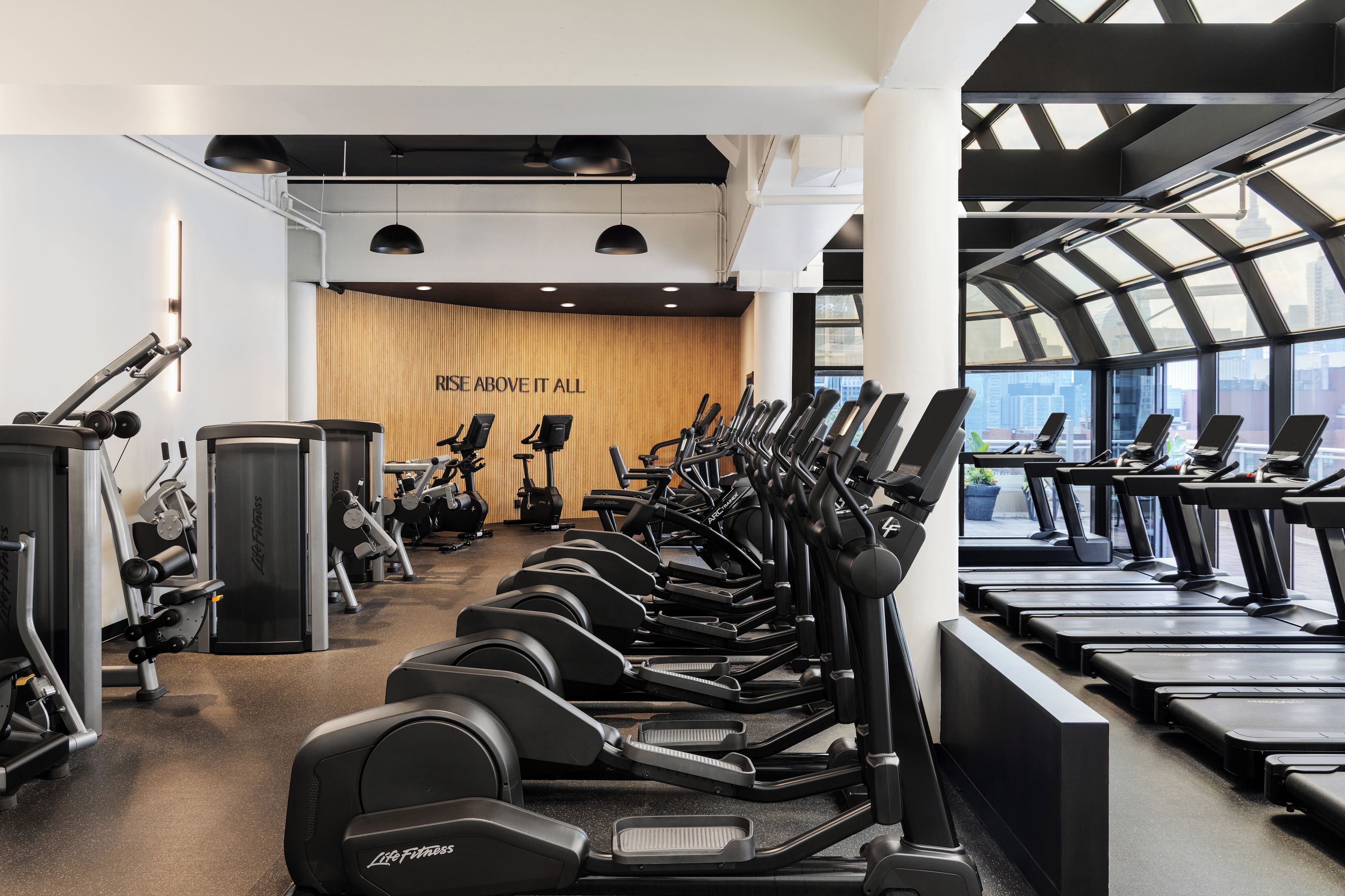 Un gimnasio con varias cintas de correr, elípticas y equipo de pesas.