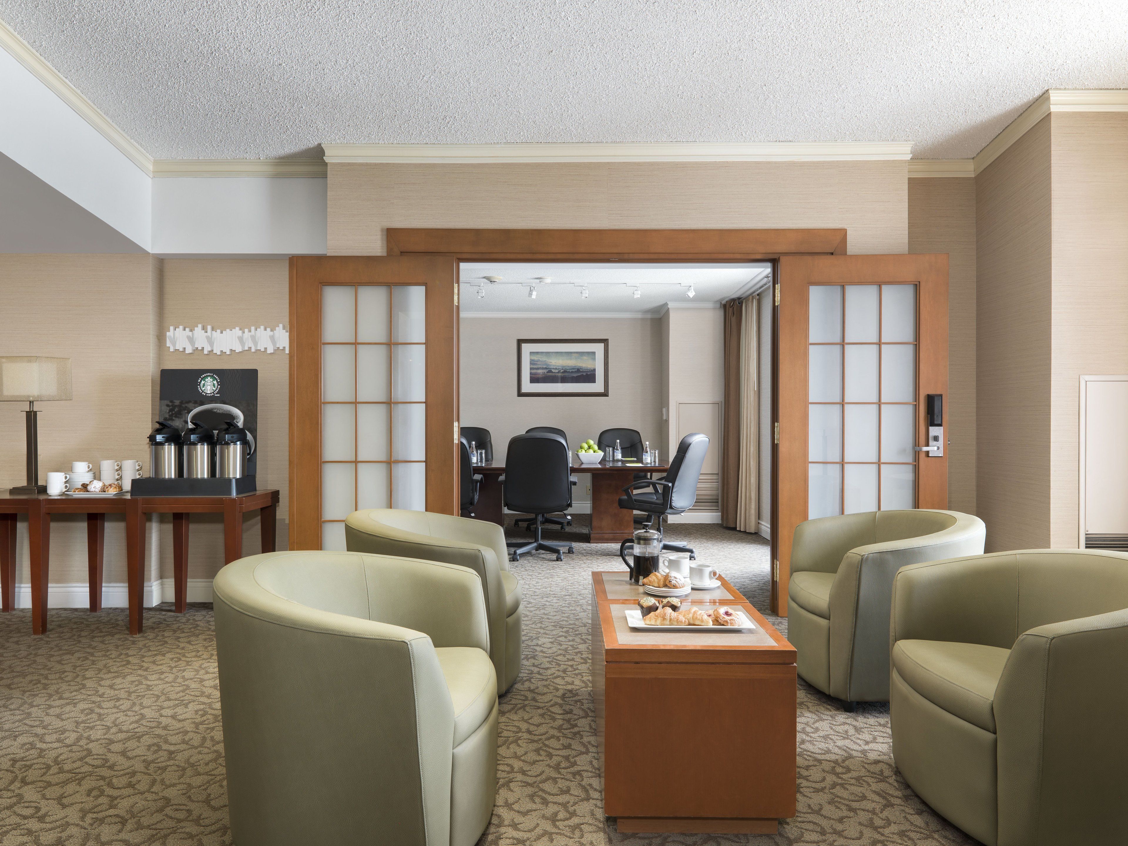 Une chambre d’hôtel dotée d’un coin salon, d’un espace pour préparer du café et donnant sur le couloir.