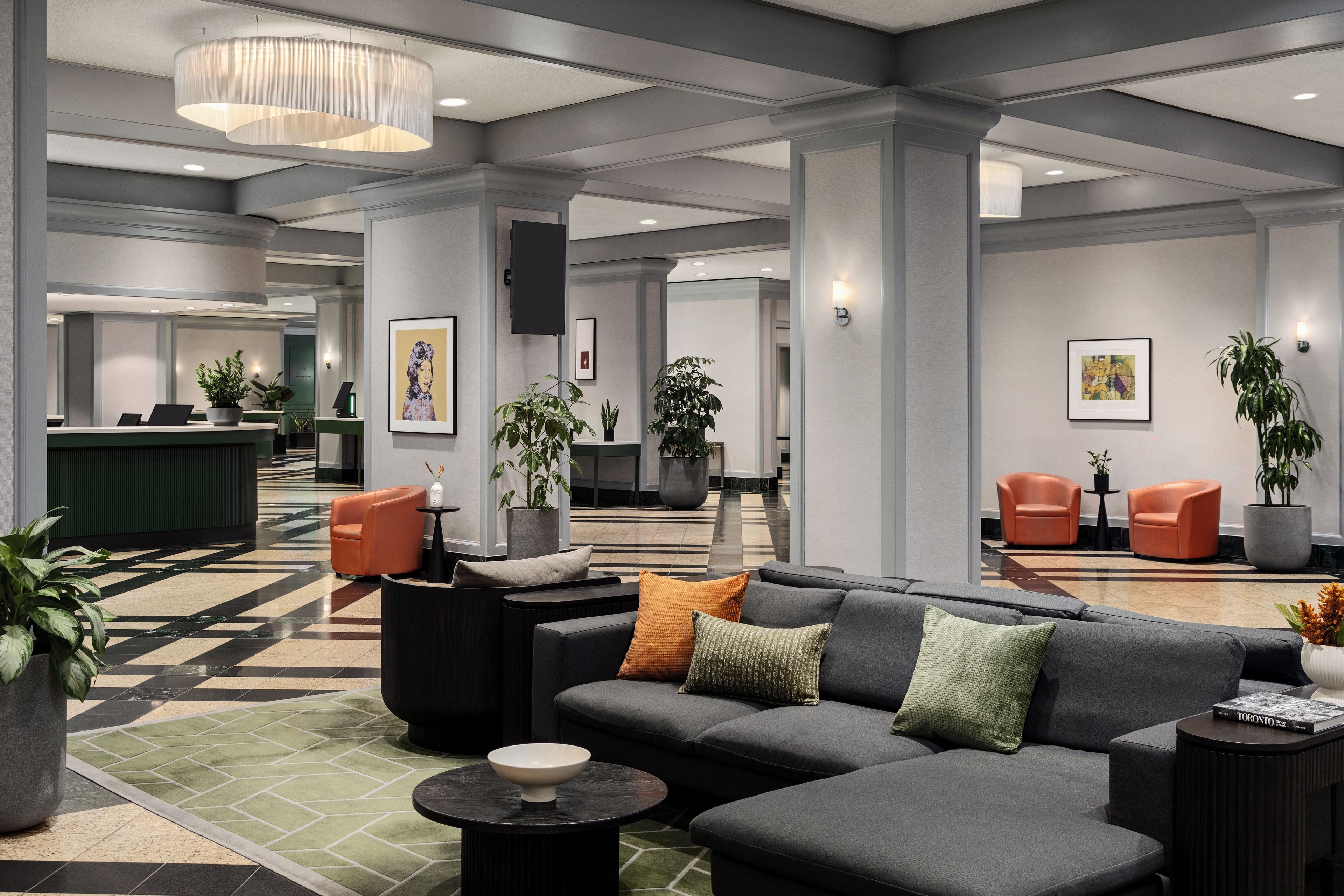 Um lobby moderno com balcão de recepção, área de estar e obras de arte nas paredes.