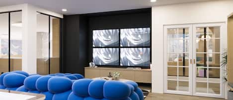 A modern room with a large blue seating area, a wooden cabinet, and a large window with curtains.