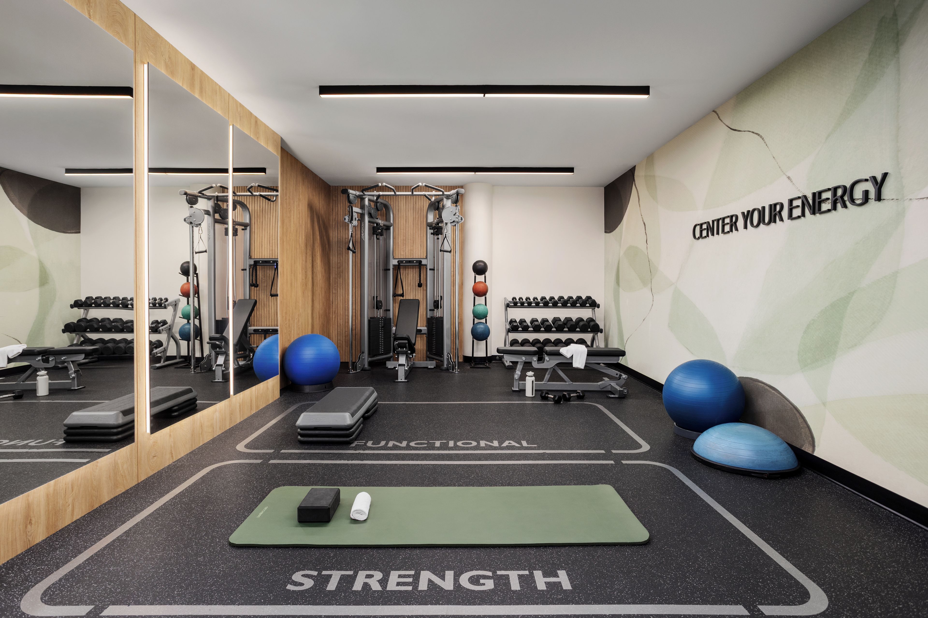 A gym with exercise equipment, a mirror, and motivational wall text.