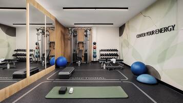 A gym with exercise equipment, a mirror, and motivational wall text.