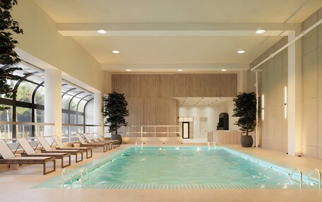 An indoor swimming pool with lounge chairs, large windows, and potted plants.