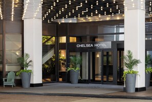 The entrance of the Chelsea Hotel with a sign, potted plants, and a staircase leading to the interior. - Chelsea Hotel, Toronto (Toronto)