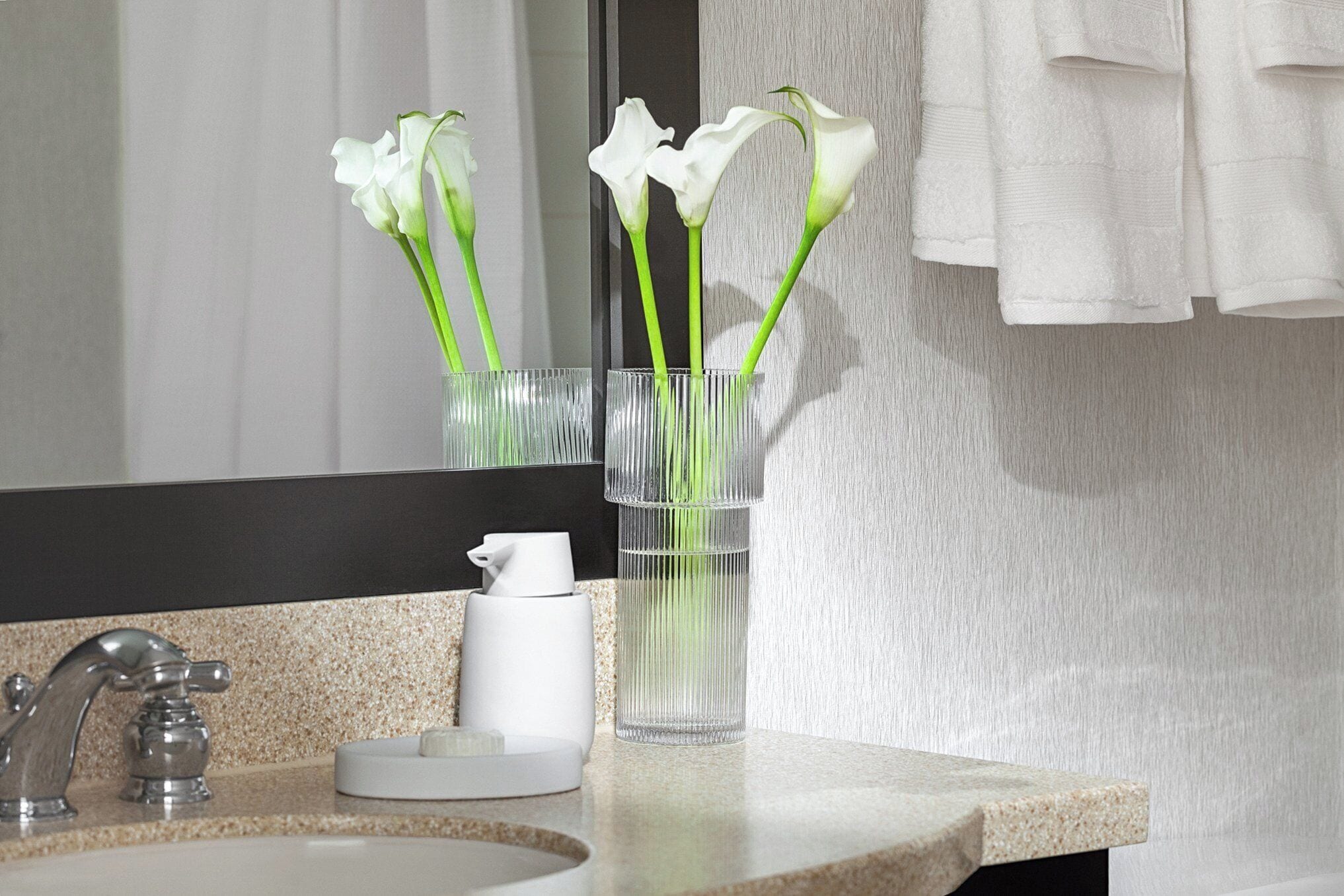 A bathroom with a sink, mirror, and towel rack.
