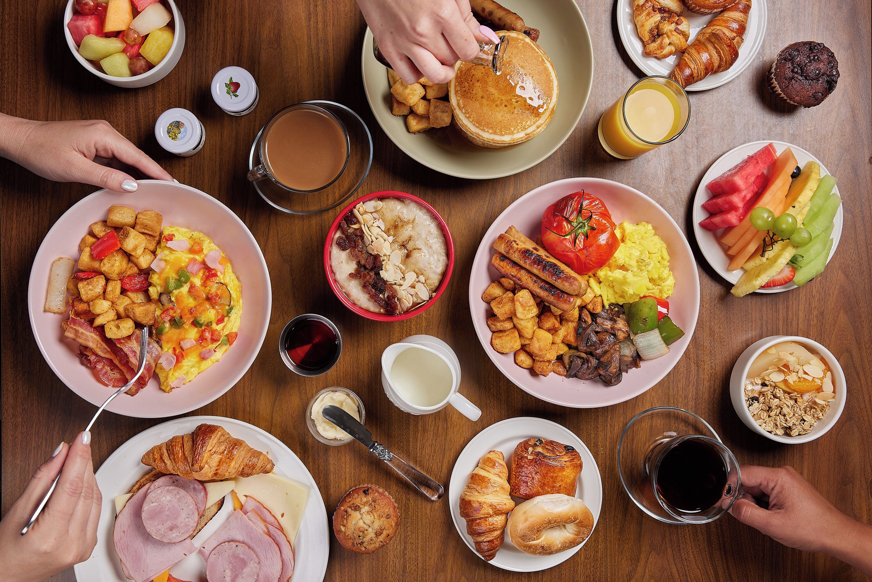 A table with various breakfast items including eggs, toast, fruits, and beverages.