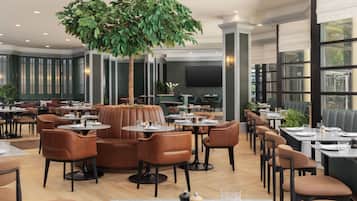 Um restaurante com várias mesas e cabines, uma grande árvore artificial e design de interiores moderno.