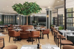 A restaurant with multiple dining tables and booths, a large artificial tree, and a modern interior design. - Chelsea Hotel, Toronto (Toronto)