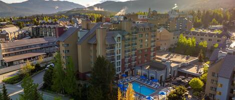 Un hotel con zona de piscina, rodeado de montañas y árboles.