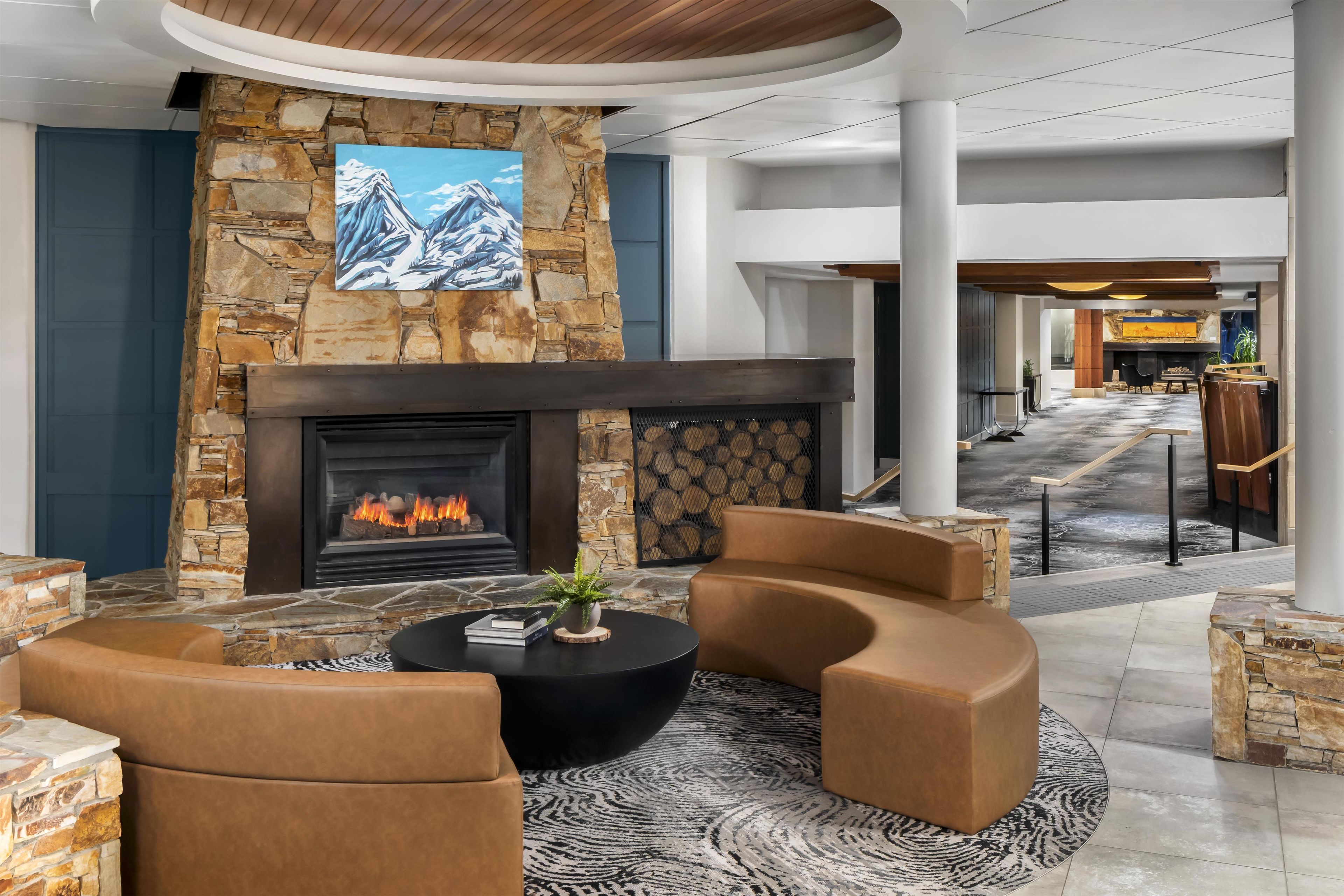 A modern lounge area with a stone fireplace, leather seating, and a large flat-screen TV mounted on the wall.