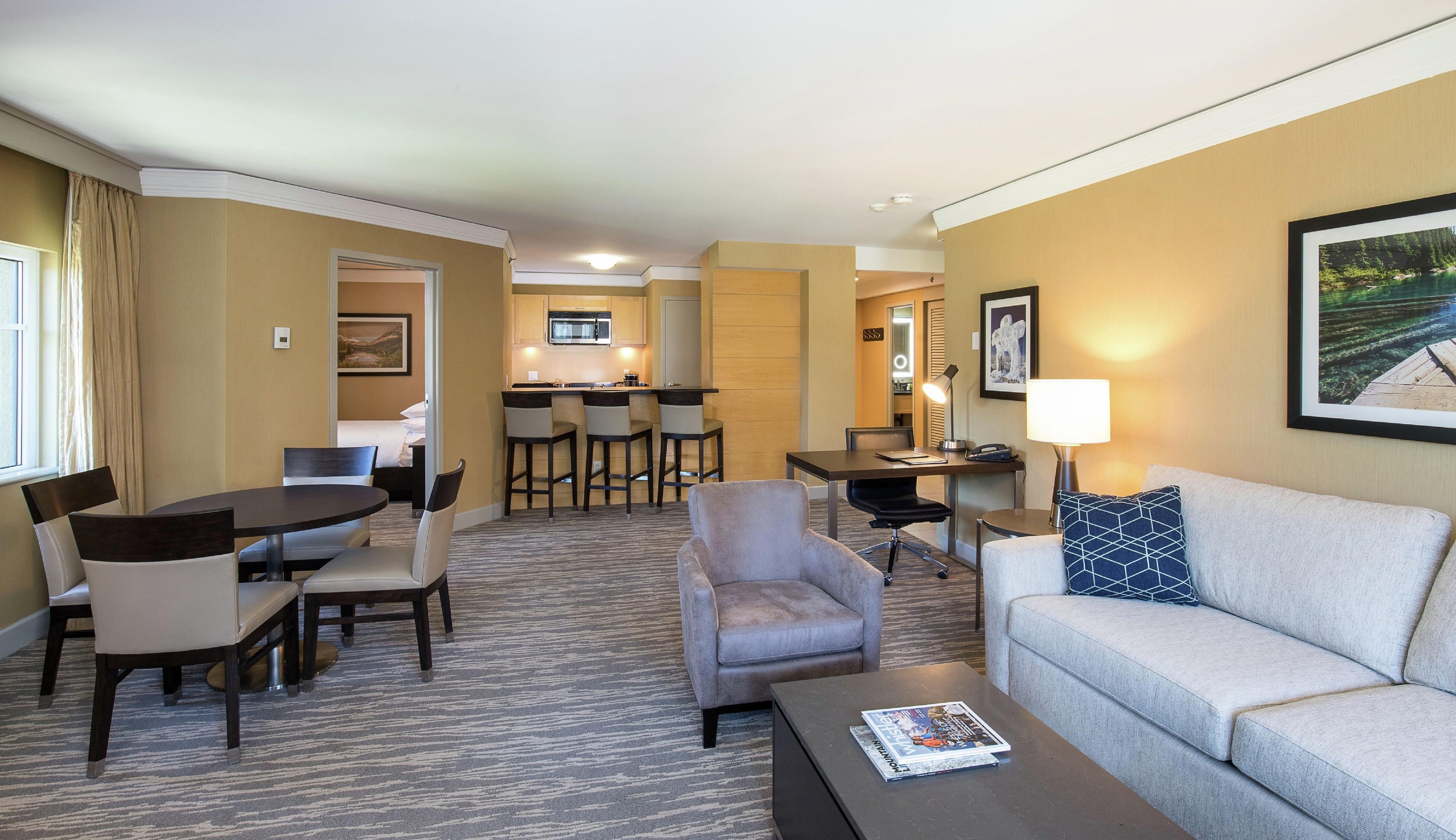 Una habitación de hotel con zona de comedor, sofá, mesa de centro y televisión.