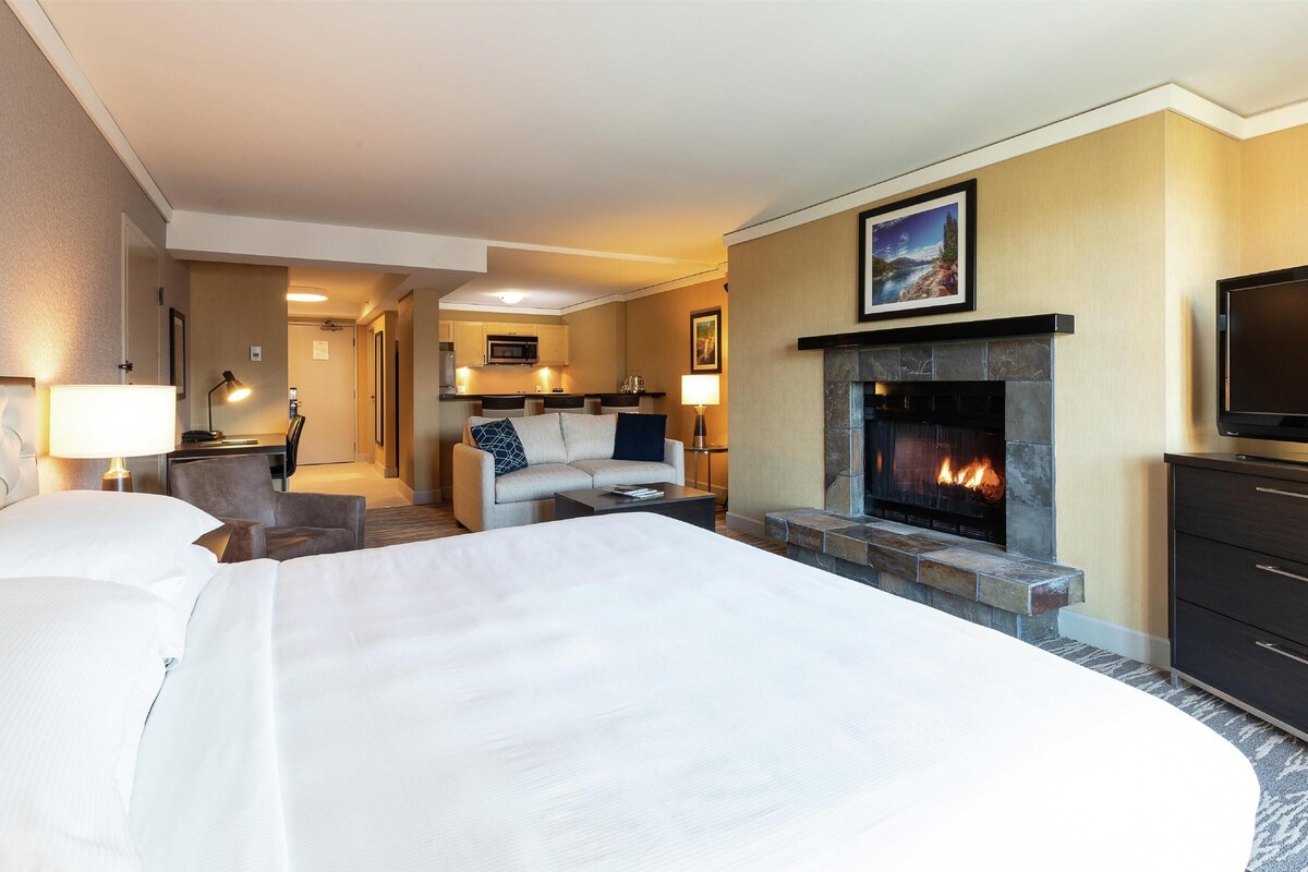 Une chambre d’hôtel avec un grand lit, un canapé, une cheminée et une télévision.