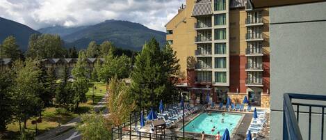 Un hotel con piscina, sillones de exterior y vistas a la montaña.