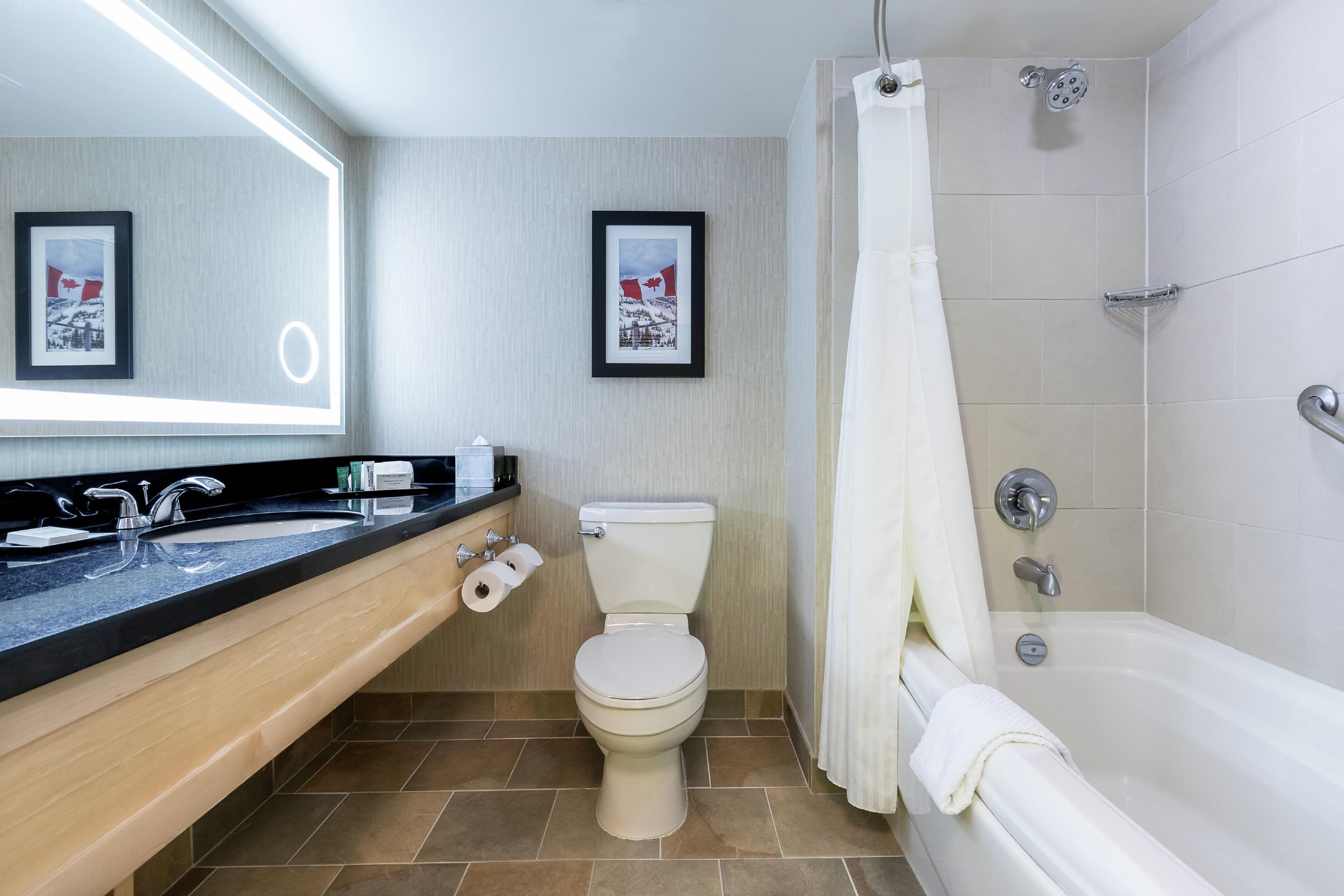 A bathroom with a bathtub, toilet, sink, and two framed pictures on the wall.