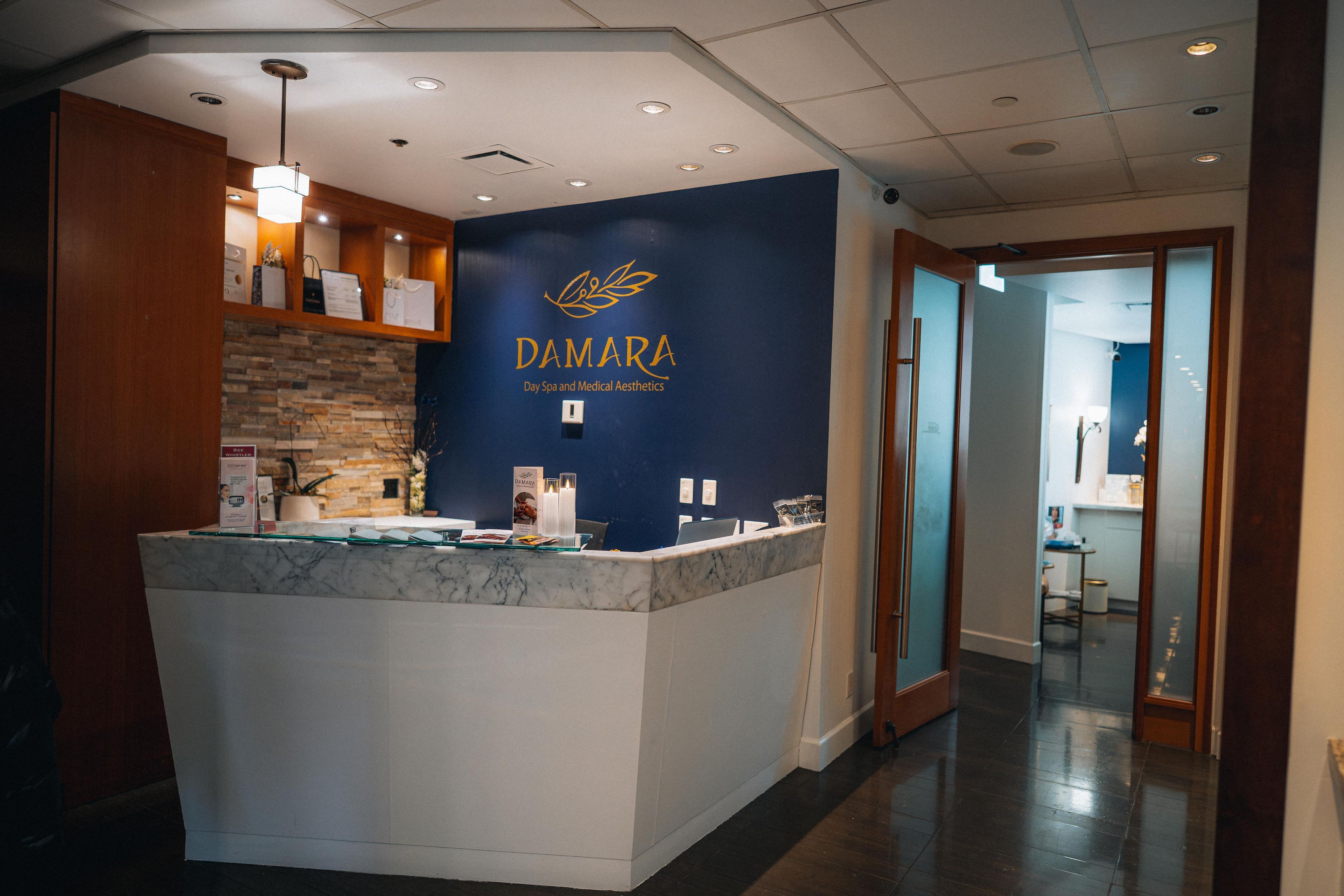 A reception desk with a marble top, a blue wall with the name 'DAMARA' and services listed, and a wooden panel on the left.