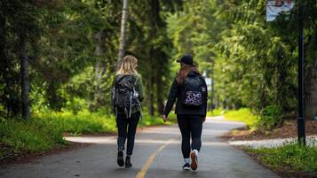 Two people walking on a paved path surrounded by trees.
