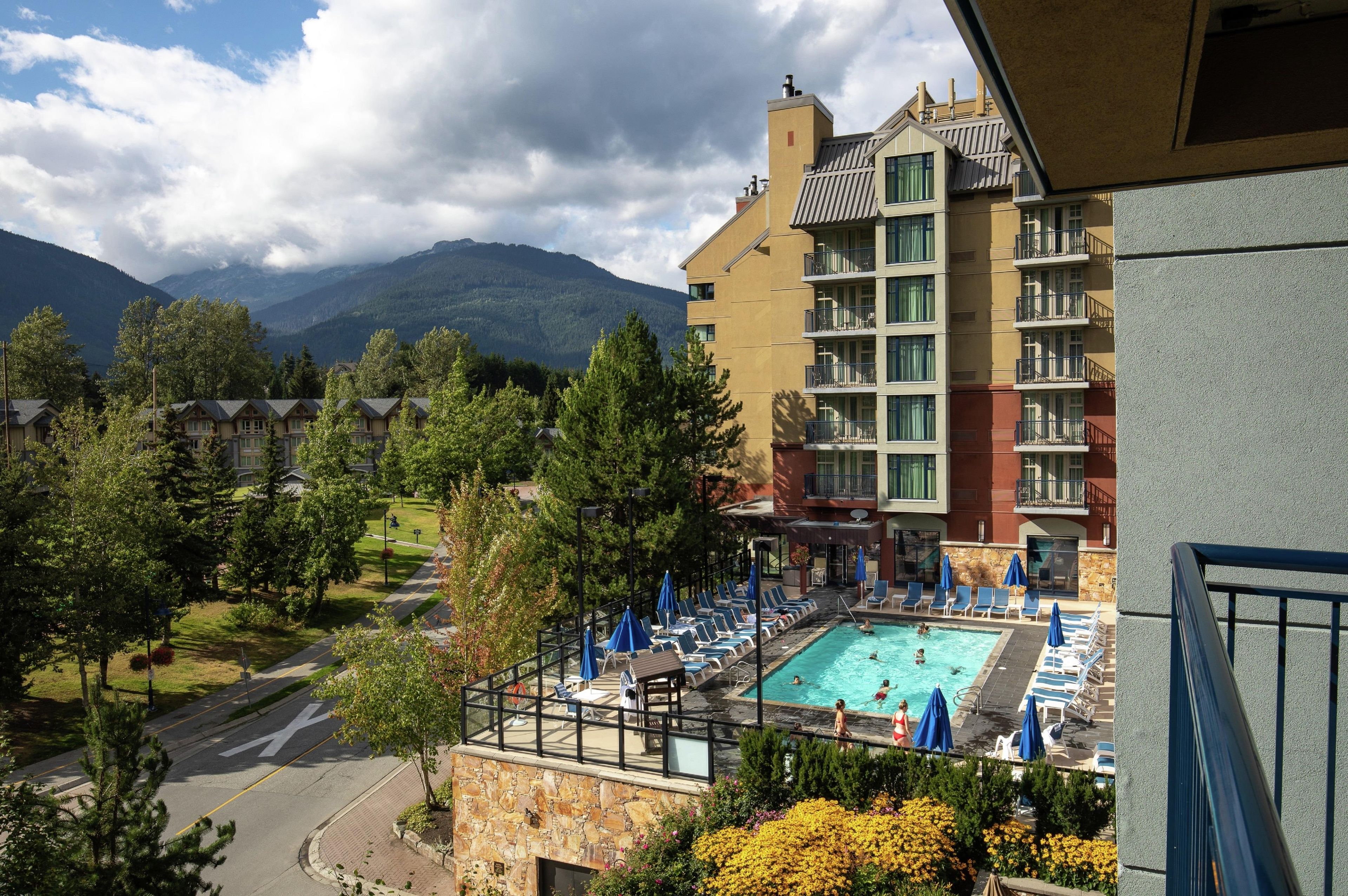 Un hotel con zona de piscina, mobiliario exterior y vistas a la montaña.