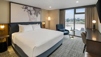 Una habitación de hotel con una cama grande, un escritorio, una silla y vistas a la ciudad.
