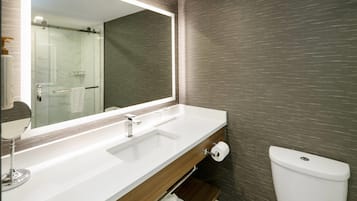 A bathroom with a large mirror, two sinks, a toilet, and a towel rack.