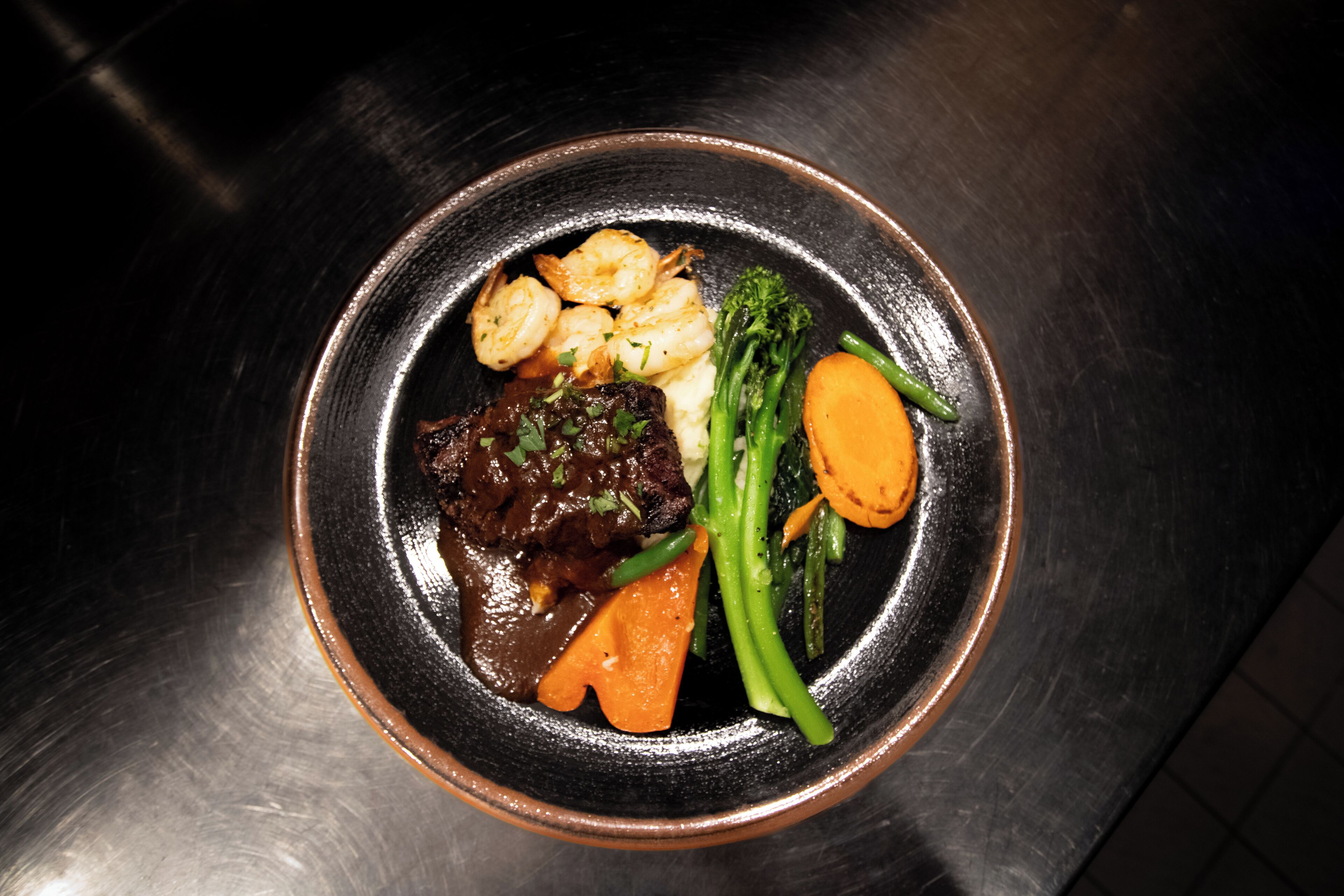 A plate of food with shrimp, beef, and vegetables.