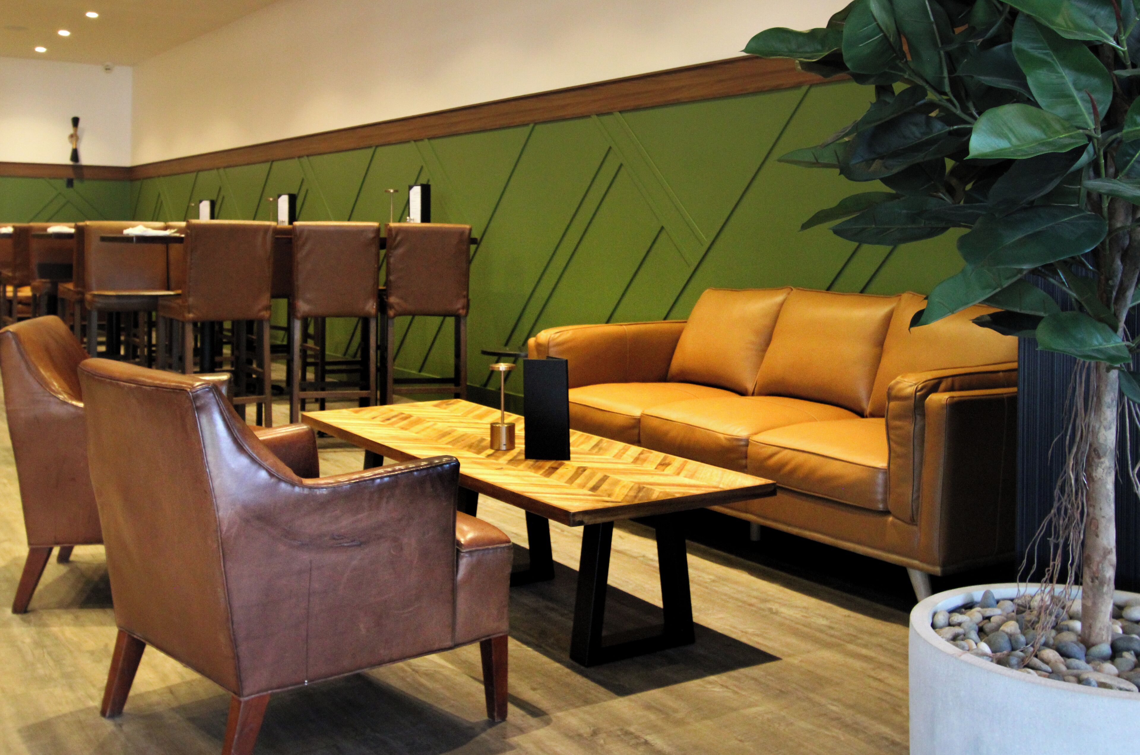 A modern lounge area with leather sofas, wooden tables, and chairs.