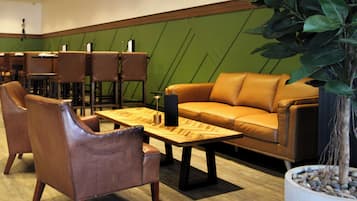 A modern lounge area with leather sofas, wooden tables, and chairs.