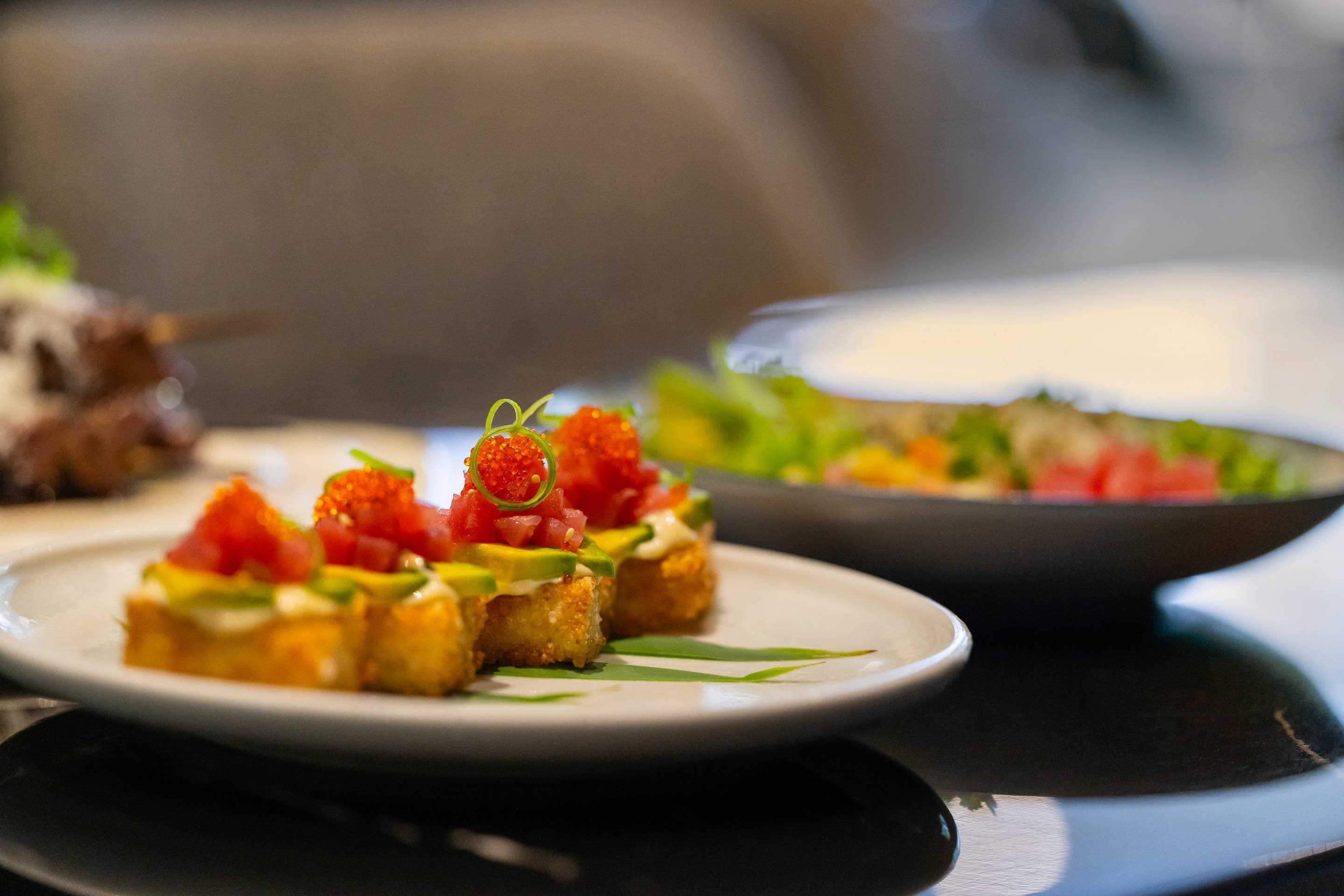 Una mesa con platos de comida, incluyendo aperitivos con huevas y aguacate.