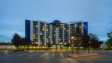 A hotel with a central entrance, multiple floors, and a parking lot.