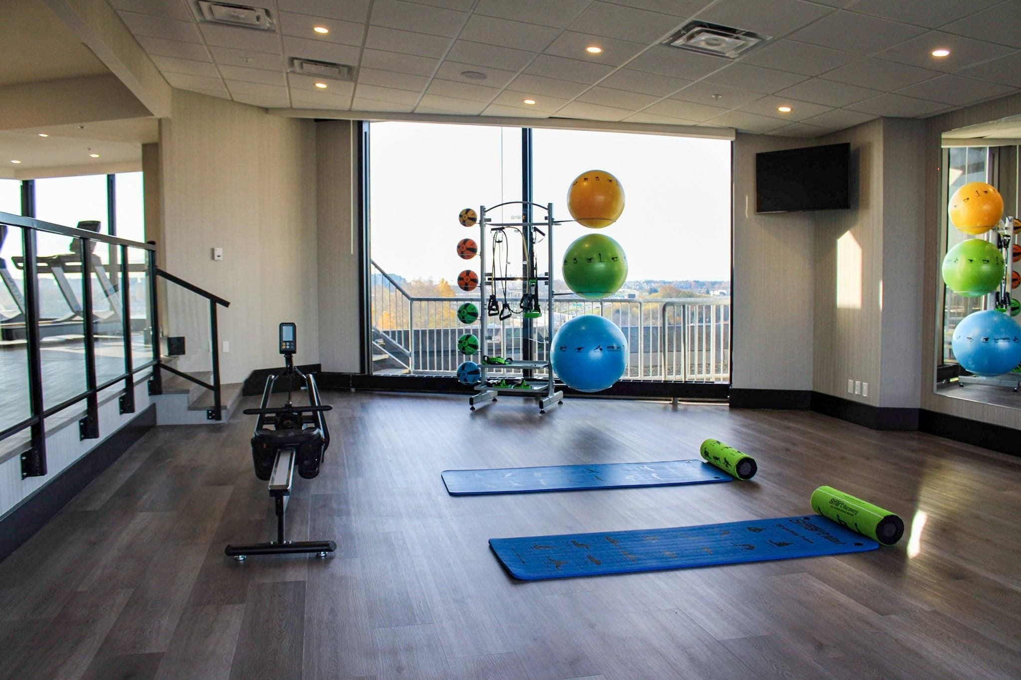 A gym with exercise equipment, large windows, and a view of the outdoors.