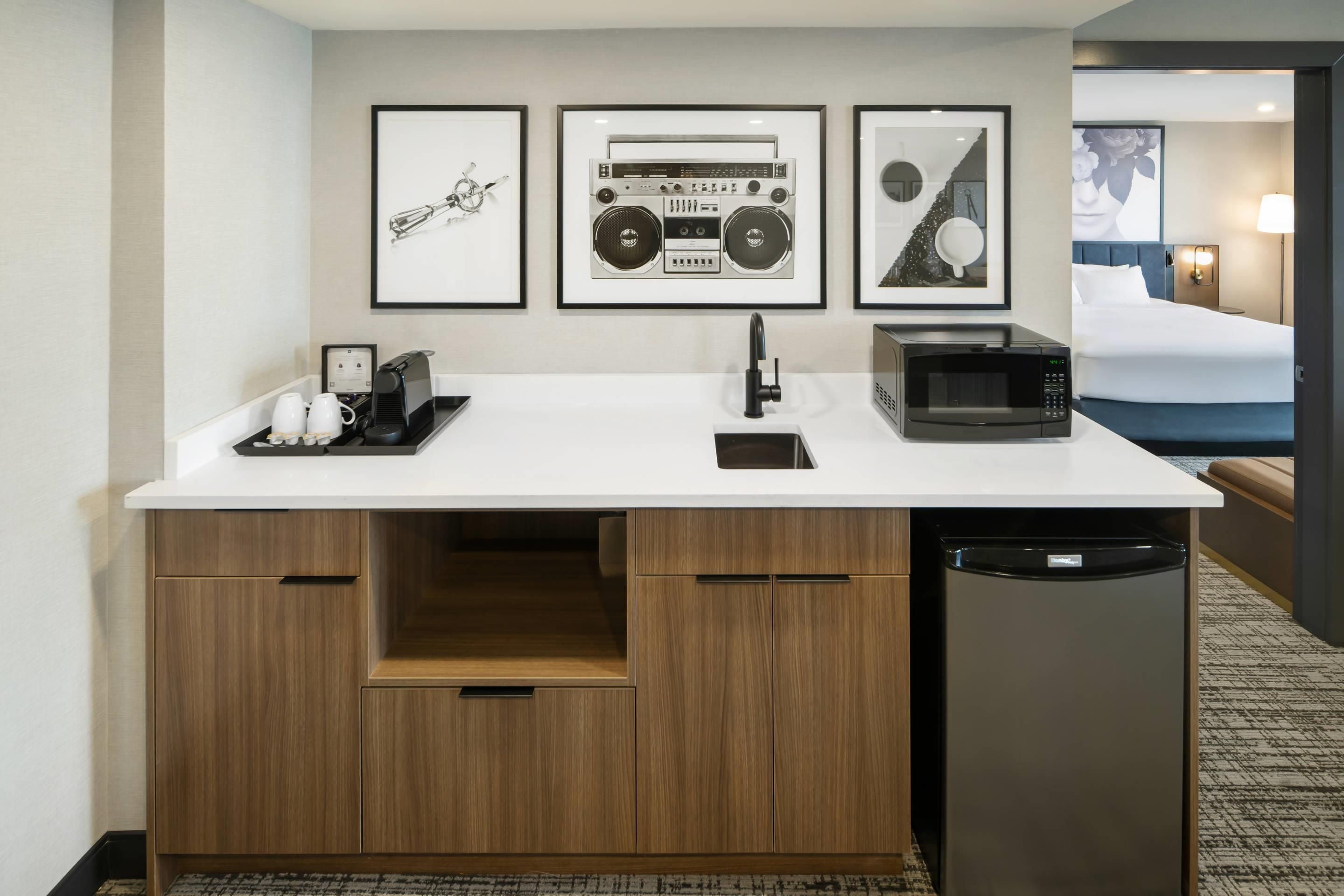 A compact hotel room with a kitchenette, a bed, and a bathroom.
