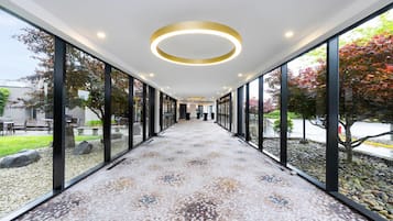 Un pasillo con suelo estampado, ventanas amplias y luces de techo circulares.